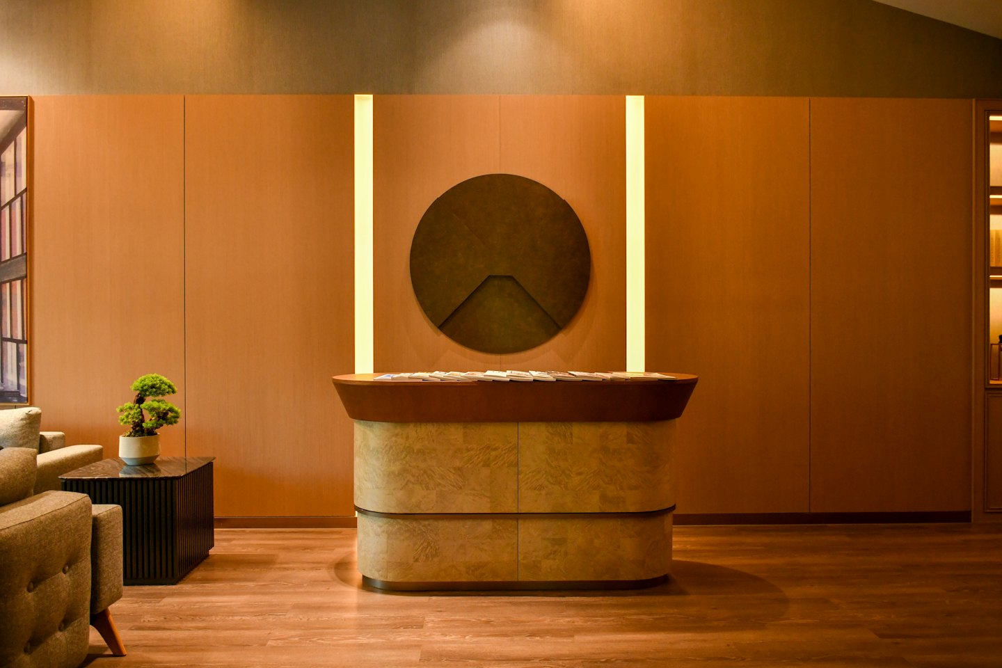 Modern reception desk with wooden top sits against paneled office wall.