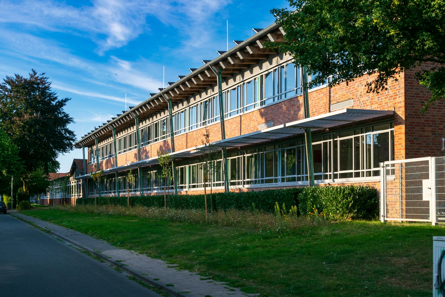 Modern brick school building with large windows beside a road.