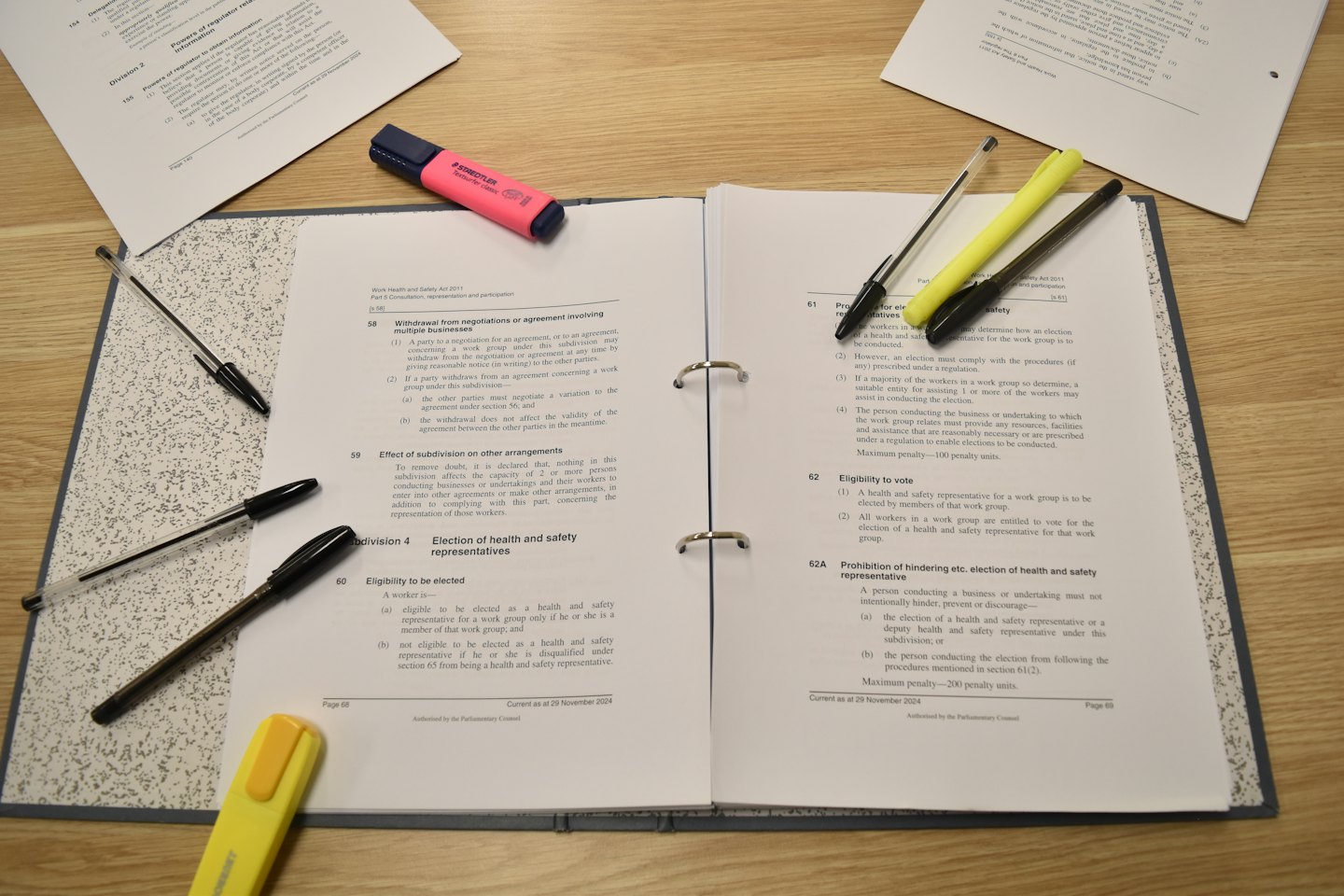 Legal documents and colorful highlighters rest on a wooden desk.