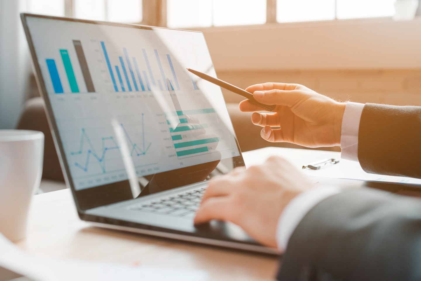 Business professional analyzing charts on a laptop screen with a stylus.