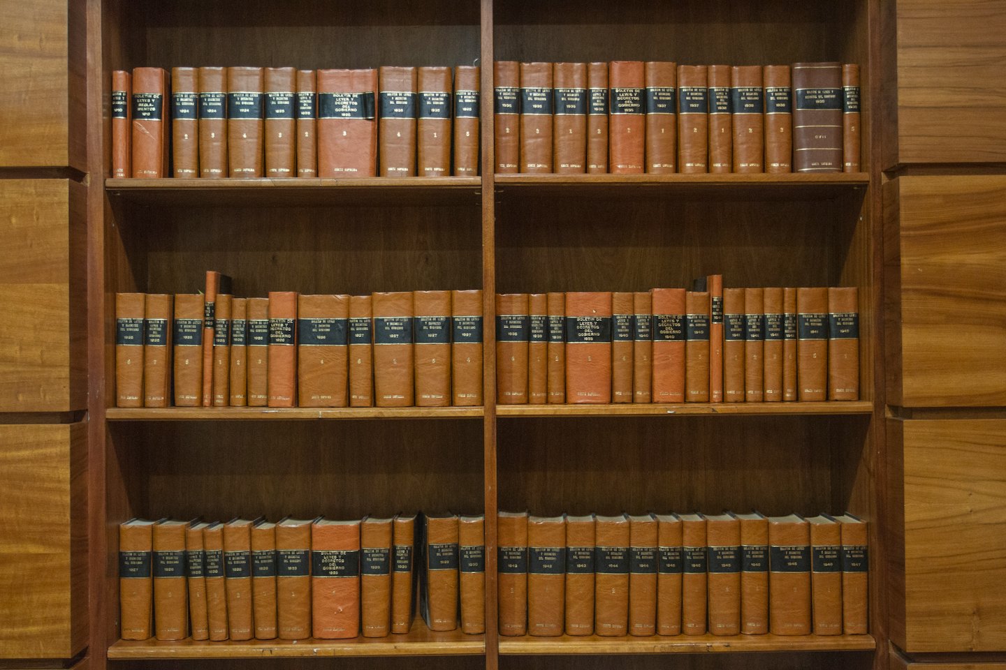 Old law books with cognac covers sit on wooden shelves.