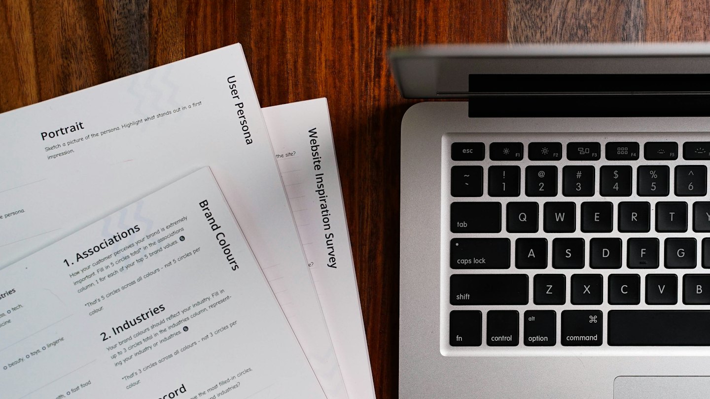 Laptop and documents on a dark wood desk.